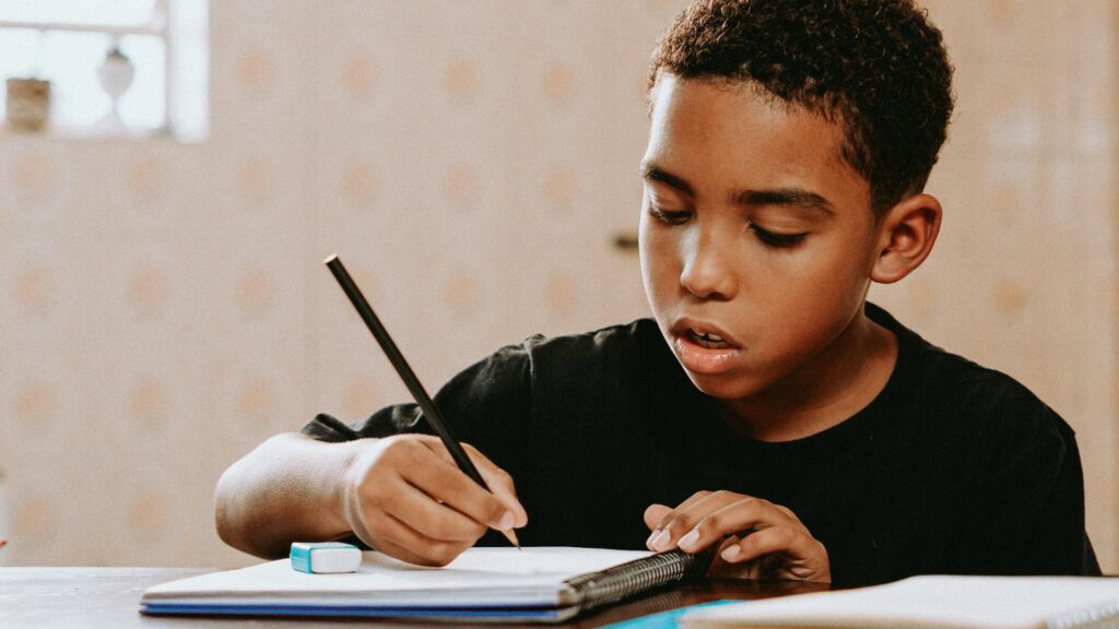 Boy focused on writing in his math notebook at the table