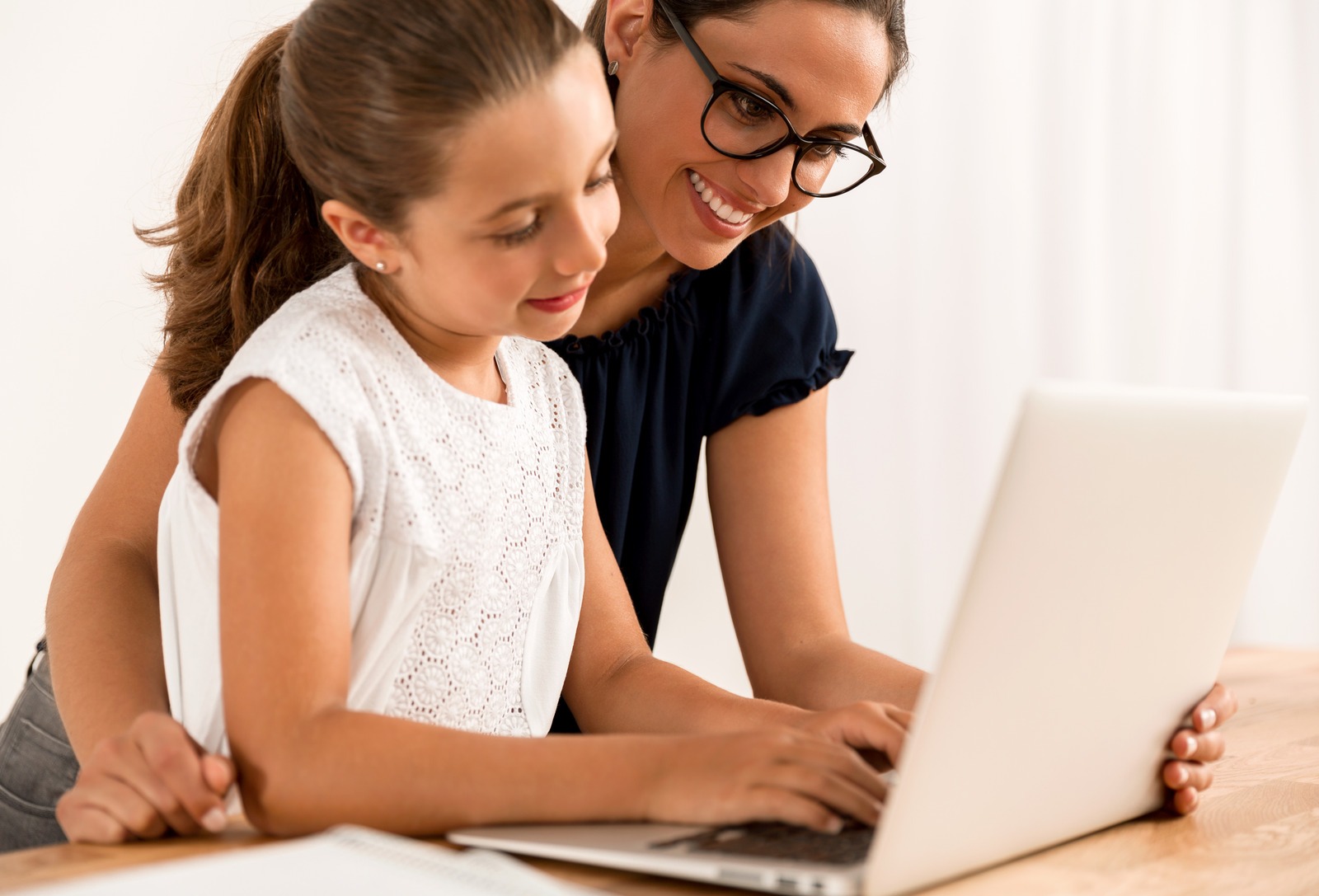 Young mother helping her daughter with Nicole the Math Lady online Saxon Math homeschool lessons on her laptop