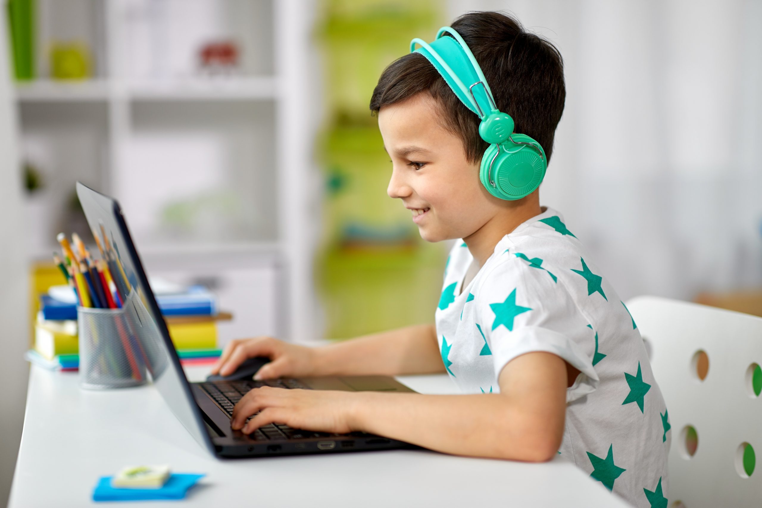 Young student smiling wearing headphones working on his Nicole the Math Lady Saxon Math homeschool lessons online on laptop.
