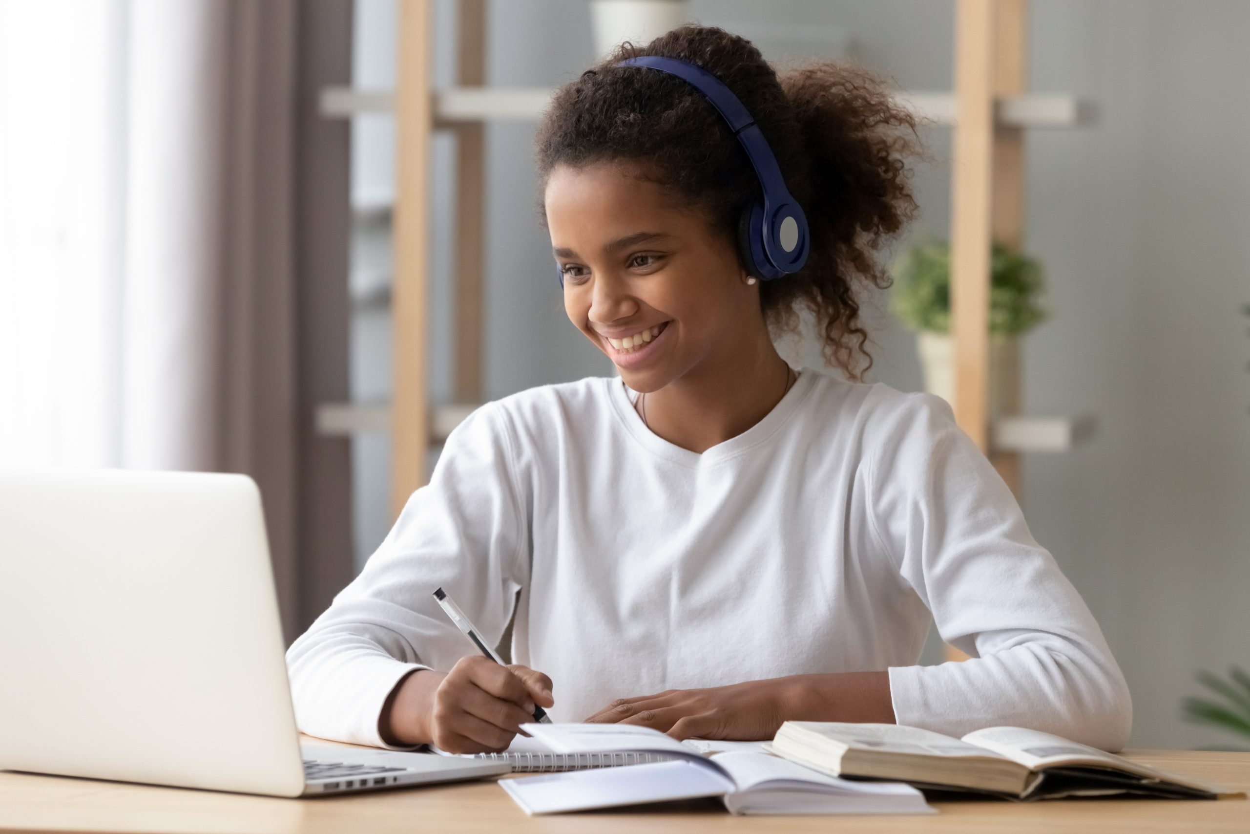 Smiling black teenage girl wearing headphones working on Nicole the Math Lady Saxon Math homeschool lessons online