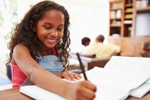 Smiling student doing homework at table.