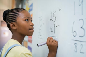 Girl doing addition problems at a whiteboard