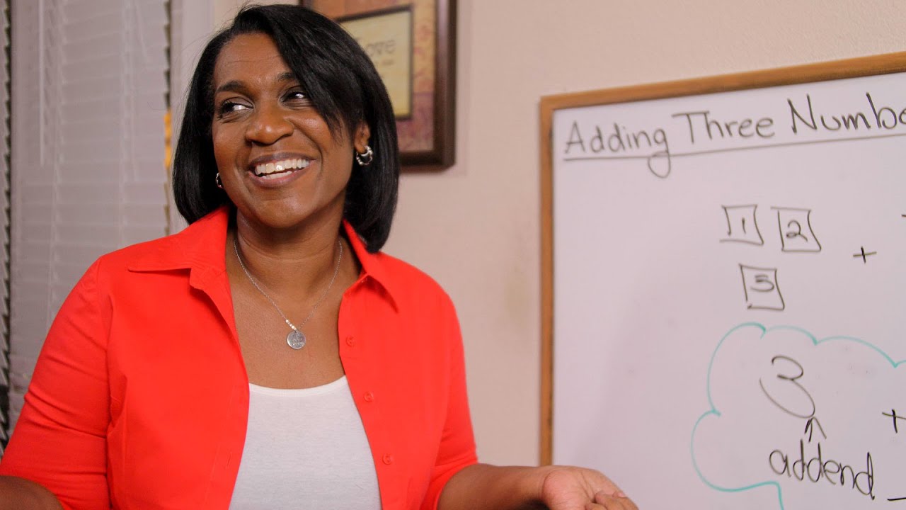 Nicole the Math Lady smiling and standing at her whiteboard